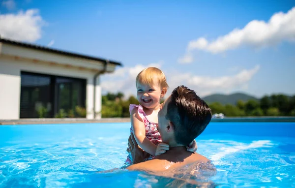 Padre joven con hija pequeña en la piscina al aire libre en el jardín del patio trasero. — Foto de Stock
