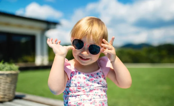 Portrait of small toddler girl with sunglasses outdoors in backyard garden. — Stock Photo, Image