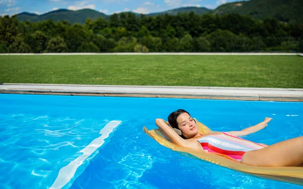 Mladá žena v bazénu venku na zahradě, relaxační. — Stock fotografie