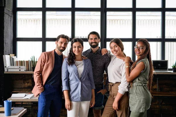 Portret van jonge zakenmensen die binnen op kantoor staan en naar de camera kijken. — Stockfoto