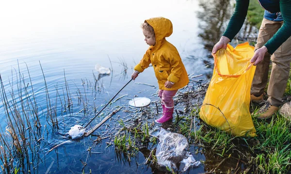 Vader met kleine dochter verzamelen van afval buiten in de natuur, plogging concept. — Stockfoto