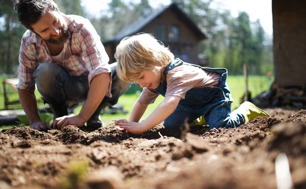 Vater mit kleinem Sohn arbeitet im Garten, nachhaltiges Lifestylekonzept. — Stockfoto