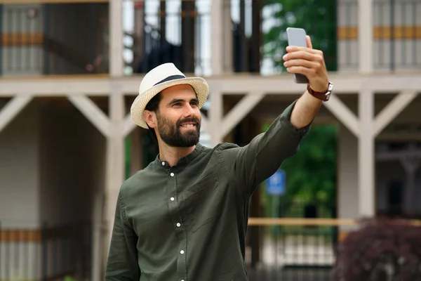 Genç adam tatilde otelin yanında duruyor, selfie çekiyor.. — Stok fotoğraf