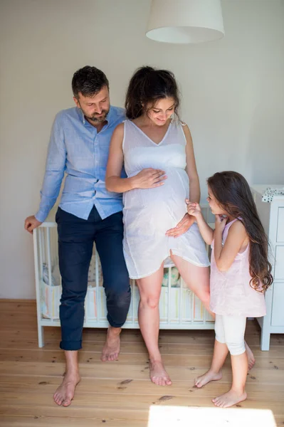Porträtt av gravid kvinna med man och liten dotter inomhus. — Stockfoto