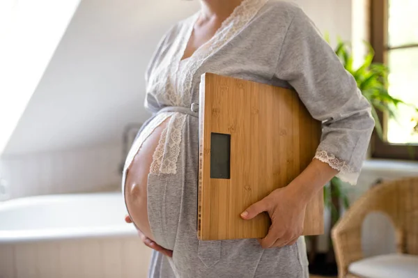 Nierozpoznawalna kobieta w ciąży w domu, nosząca łuski. — Zdjęcie stockowe