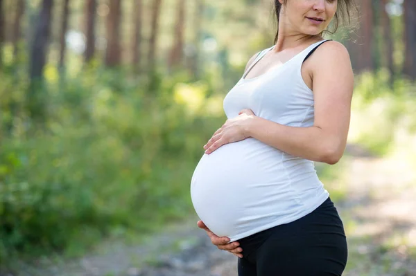 Oigenkännlig gravid kvinna utomhus i naturen, röra hennes mage. — Stockfoto