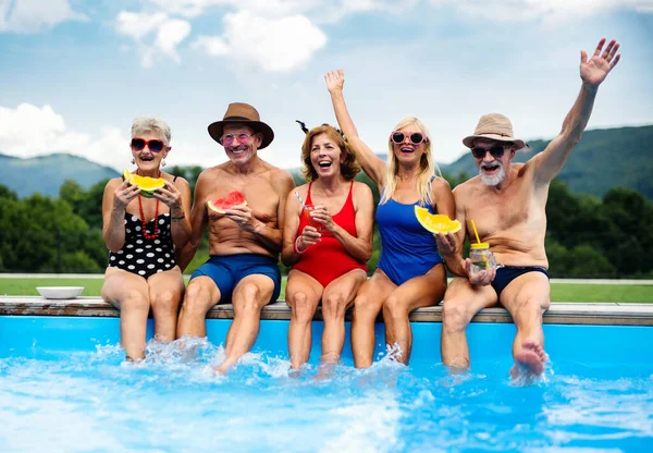 Skupina veselých seniorů sedících venku u bazénu na dvorku. — Stock fotografie