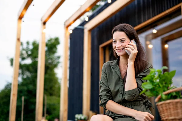 Giovane donna con smartphone all'aperto, fine settimana in casa container in campagna. — Foto Stock