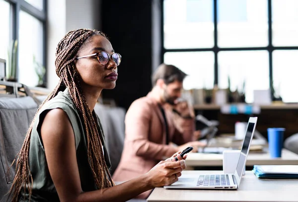 Ritratto di giovani imprenditori con laptop che lavorano al chiuso in ufficio. — Foto Stock