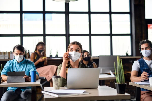 Potret para pengusaha muda dengan topeng wajah yang bekerja di dalam ruangan di kantor. — Stok Foto