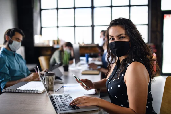 Portret van jonge ondernemers met gezichtsmaskers die binnen in het kantoor werken. — Stockfoto