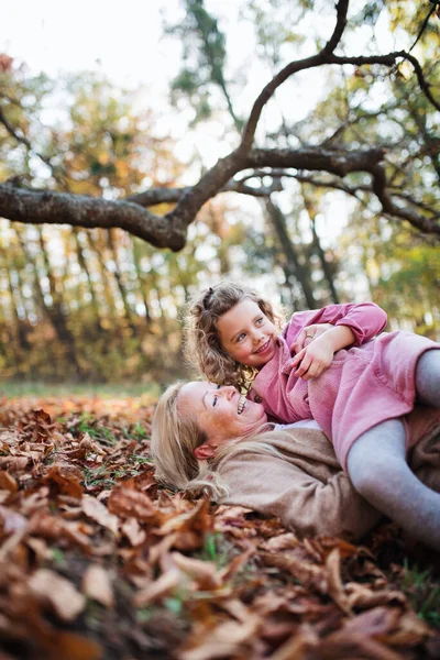 Sonbahar ormanında büyükannesiyle yürüyüşe çıkmış küçük bir kız, eğleniyor.. — Stok fotoğraf