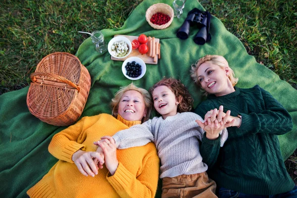 Draufsicht eines kleinen Mädchens mit Mutter und Großmutter beim Picknick in der Natur. — Stockfoto
