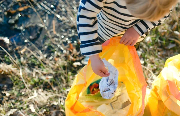 Onherkenbaar klein kind verzamelt afval buiten in de natuur, plogging concept. — Stockfoto