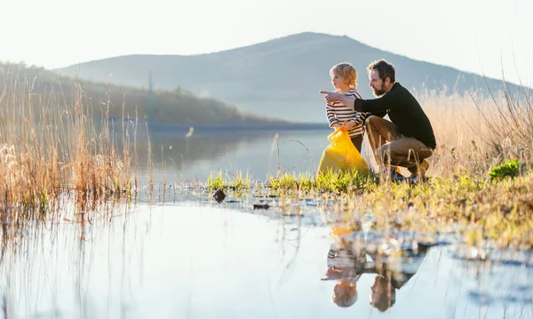 Padre con hijo pequeño recogiendo basura al aire libre en la naturaleza, el concepto de trote. — Foto de Stock