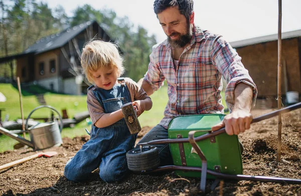 Vader met kleine zoon die buiten in de tuin werkt, duurzaam lifestyle concept. — Stockfoto