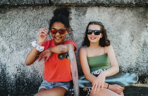 Młody nastolatek dziewczyny przyjaciele z deskorolki na świeżym powietrzu w mieście, siedzi. — Zdjęcie stockowe
