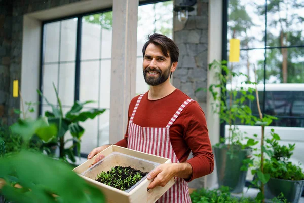 Portrait of man gardener standing in greenhouse, looking at camera. — Stok Foto