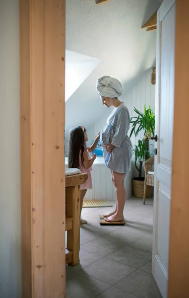 Retrato de mulher grávida com pequena filha dentro de casa de banho em casa. — Fotografia de Stock