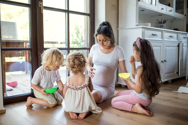 Gravid kvinna med små barn inomhus, pratar. — Stockfoto