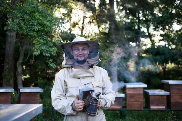 Retrato del apicultor que trabaja en el colmenar, sosteniendo a un fumador de abejas. — Foto de Stock