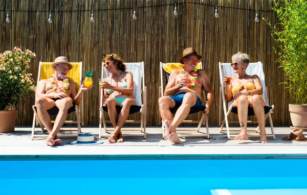 Group of cheerful seniors sitting by swimming pool outdoors in backyard. — Stock Photo, Image