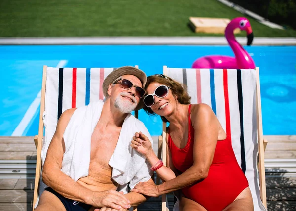 Весела старша пара сидить біля басейну на відкритому повітрі на подвір'ї . — стокове фото