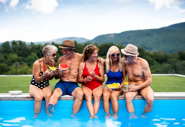 Skupina veselých seniorů sedících venku u bazénu na dvorku. — Stock fotografie