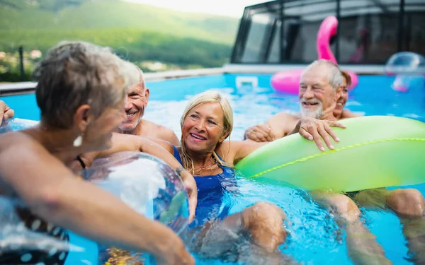 Група веселих літніх людей у басейні на відкритому повітрі на подвір'ї, розмова . — стокове фото