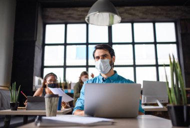 Ofiste yüz maskesi takan iş adamları Coronavirus tecridinden sonra işe geri dönüyorlar..