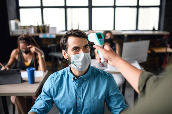 Orang bisnis dengan masker wajah mengukur suhu di kantor, konsep coronavirus. — Stok Foto
