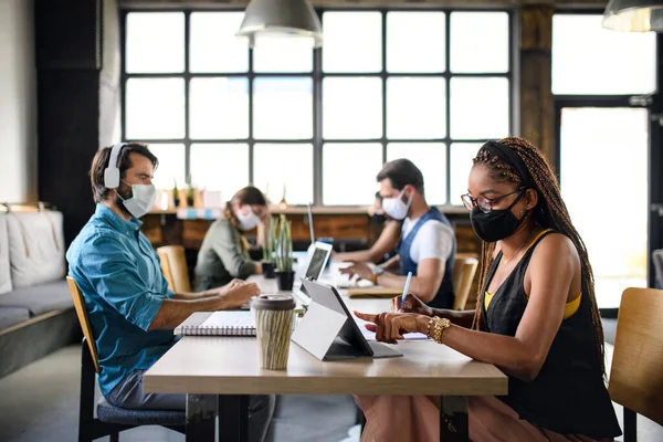 Affärsmän med ansiktsmasker inomhus på kontoret, tillbaka till arbetet efter coronavirus nedstängning. — Stockfoto