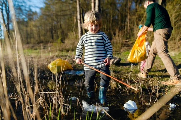 Ayah dengan anak-anak kecil mengoleksi sampah di alam, konsep plogging. — Stok Foto