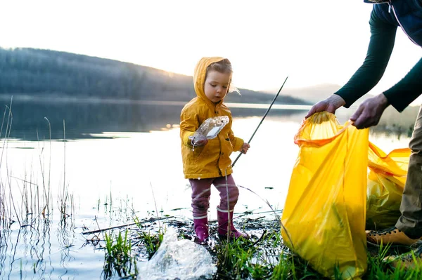 Vader met kleine dochter verzamelen van afval buiten in de natuur, plogging concept. — Stockfoto