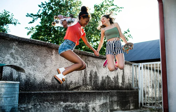 Młody nastolatek dziewczyny przyjaciele z deskorolki na świeżym powietrzu w mieście, skoki. — Zdjęcie stockowe