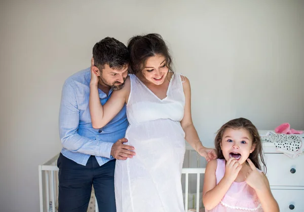 Portrait de femme enceinte avec mari et petite fille à l'intérieur à la maison. — Photo