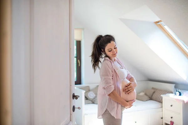 Портрет счастливой беременной женщины в помещении дома, трогающей живот. — стоковое фото