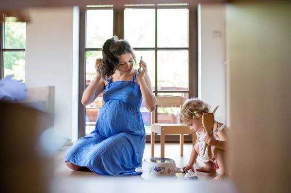 Kobieta w ciąży z małym dzieckiem w domu, za pomocą smartfona. — Zdjęcie stockowe