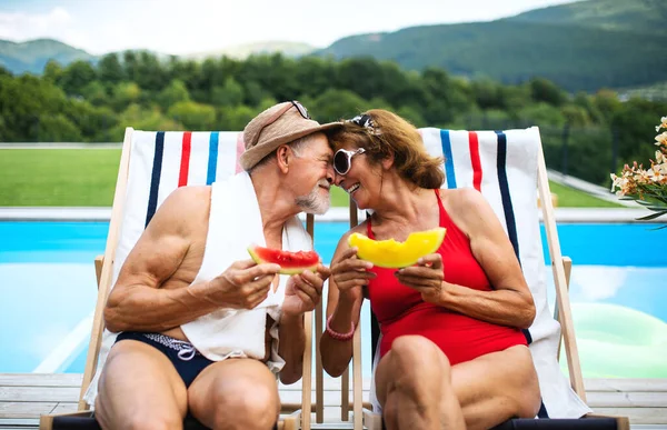 Старша пара в любові сидить біля басейну на відкритому повітрі на подвір'ї . — стокове фото