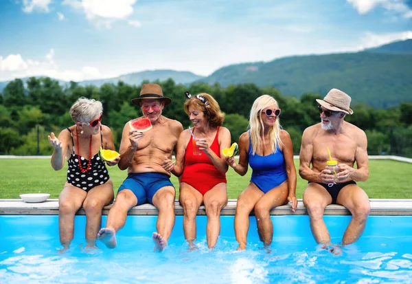 裏庭で屋外プールに座っている陽気な高齢者のグループ. — ストック写真