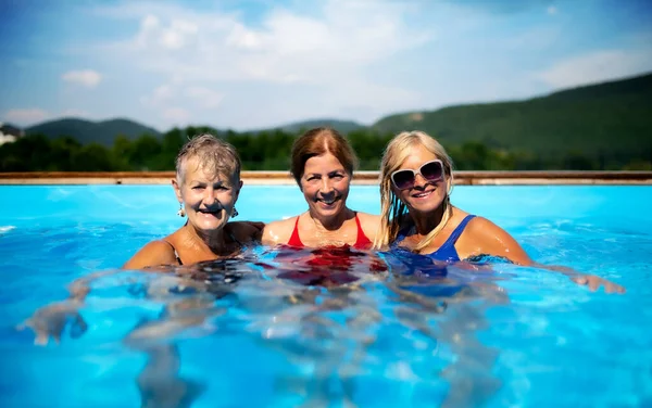 Vista frontal de mujeres mayores alegres en la piscina al aire libre en el patio trasero. —  Fotos de Stock