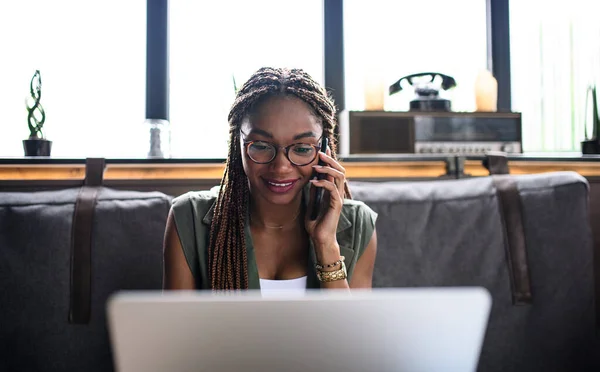 Giovane donna d'affari con laptop e smartphone che lavora al chiuso in ufficio. — Foto Stock