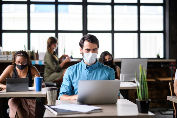 Affärsmän med ansiktsmasker inomhus på kontoret, tillbaka till arbetet efter coronavirus nedstängning. — Stockfoto