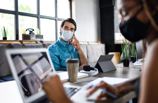 Affärsmän med ansiktsmasker inomhus på kontoret, tillbaka till arbetet efter coronavirus nedstängning. — Stockfoto