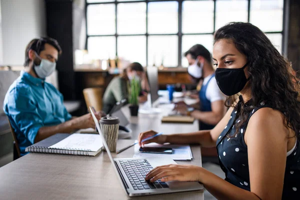 Zakenmensen met gezichtsmaskers binnen in kantoor, weer aan het werk na afsluiting van het coronavirus. — Stockfoto