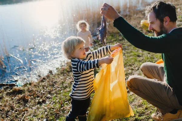 Vader met kleine kinderen verzamelen van afval buiten in de natuur, plogging concept. — Stockfoto