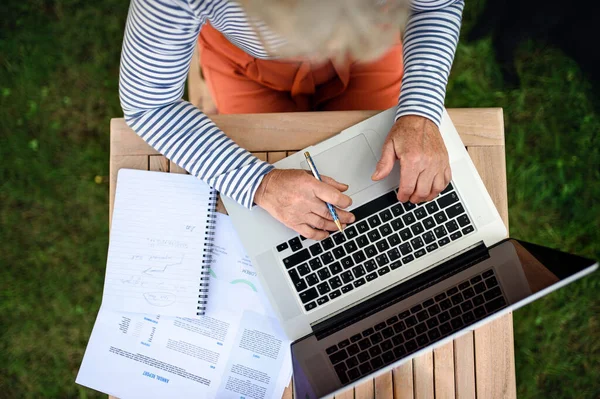 Visão superior da mulher sênior com laptop trabalhando ao ar livre no jardim, conceito de escritório em casa. — Fotografia de Stock