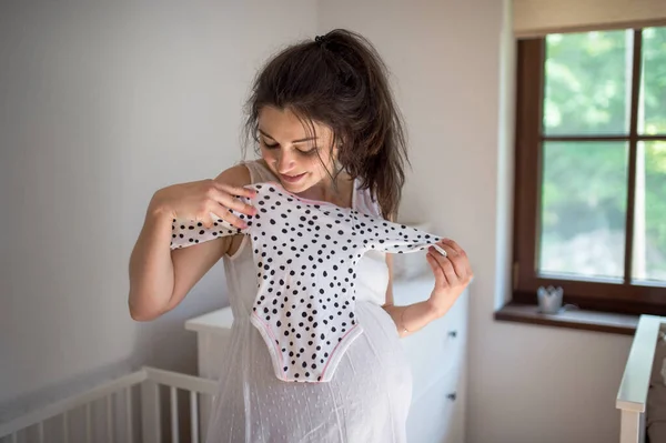 Porträt einer schwangeren Frau zu Hause, die einen Mädchenbody trägt. — Stockfoto