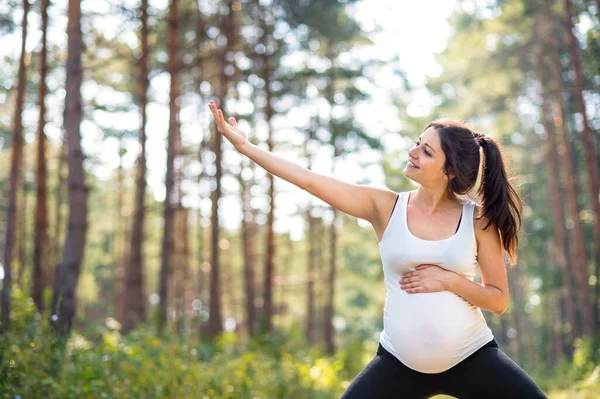 Porträtt av lycklig gravid kvinna utomhus i naturen, gör motion. — Stockfoto