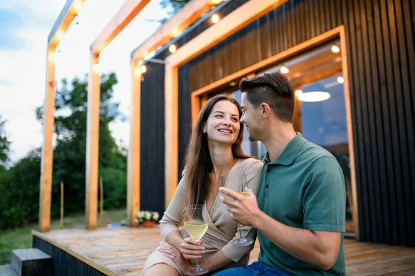 Jonge echtpaar met wijn buiten, weekend weg in container huis op het platteland. — Stockfoto